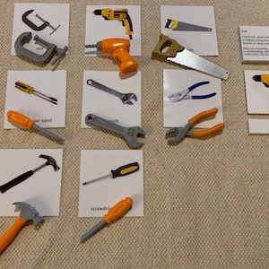 Peut inclure: Un ensemble de 10 cartes illustrant différents outils, dont un étau, un tournevis, un marteau, une clé, une pince, une scie et une perceuse. Chaque carte présente une image de l'outil et son nom écrit en dessous.