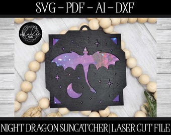May include: A black laser cut design of a night dragon with a galaxy pattern, a crescent moon, and stars. The design is for a suncatcher and is labeled "Night Dragon Suncatcher | Laser Cut File".
