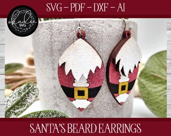 Puede incluir: Un par de pendientes de madera con forma de cara de Papá Noel. Los pendientes están pintados de rojo, blanco y negro con una hebilla de cinturón dorada. Los pendientes cuelgan de ganchos plateados.