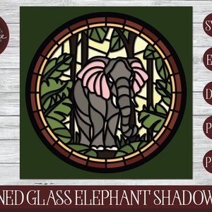 May include: A stained glass elephant shadowbox design. The image features a gray elephant with pink ears, surrounded by green foliage and trees, within a circular frame. The design includes the text "STAINED GLASS ELEPHANT SHADOWBOX".