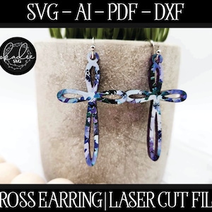 May include: A pair of cross-shaped earrings with a floral pattern in shades of purple, blue, and white. The earrings are hanging from silver hooks. The text "SVG-AI-PDF-DXF" and "CROSS EARRING|LASER CUT FILE" is visible at the top and bottom of the image.
