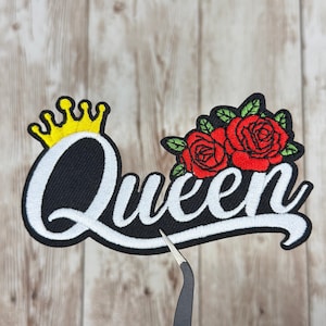 May include: Embroidered patch with the word "Queen" in white script on a black base. A yellow crown is above the "Q", and red roses with green leaves are on the right side of the word.