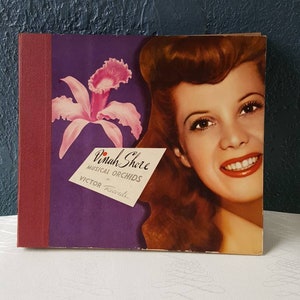 May include: A vintage record album cover featuring Dinah Shore with a pink orchid and the text "Dinah Shore Musical Orchids on Victor Records."