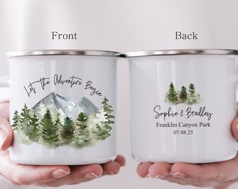 Könnte beinhalten: Zwei weiße Emaille-Campingbecher mit einer Wald- und Bergszene. Der vordere Becher trägt die Aufschrift "Let the Adventure Begin" und der hintere Becher die Aufschrift "Sophie & Bradley, Franklin Canyon Park, 07.08.25".