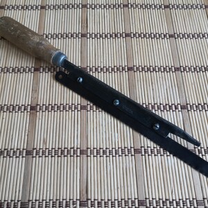 May include: A vintage, black metal, folding utility knife with a wooden handle. The blade is partially open and has a small metal tab with the word "GORDON" printed on it.