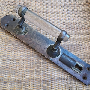Könnte beinhalten: Antiker Türgriff aus Messing mit einem durchsichtigen Glas- und Holzknopf. Der Griff ist auf einer Messingplatte mit einem Schlüsselloch und Schrauben montiert.