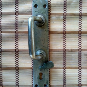 May include: A vintage brass door handle with a lever and a keyhole. The handle is mounted on a wooden surface.