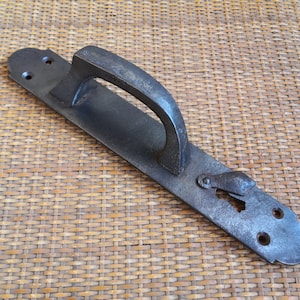 May include: A dark gray, antique-style door handle with a curved grip and a rectangular backplate. The handle features a keyhole and mounting holes, suggesting a vintage or rustic aesthetic. The metal appears to have a textured finish.