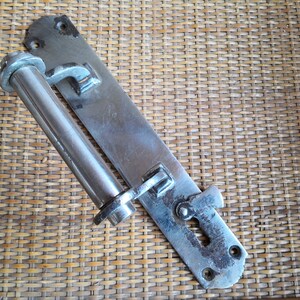May include: A silver metal door latch with a long, cylindrical handle. The latch is mounted on a metal plate with a keyhole and a small lever.