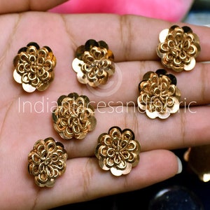 May include: Gold flower-shaped embellishments with a raised design. The embellishments are approximately 2.5 cm in diameter and are ideal for adding a touch of sparkle to any project.