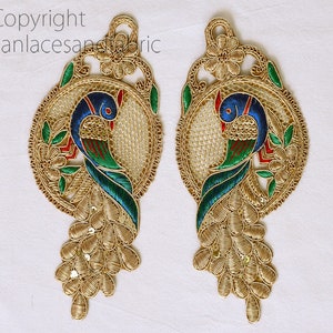 May include: Two gold embroidered peacock appliques with blue, green, and red accents. The peacocks are surrounded by a circular design with floral details.