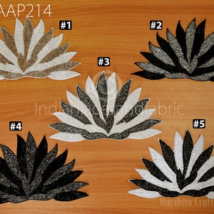 May include: Five beaded lotus flower appliques in different colour combinations. The appliques are black, white, and gold. The appliques are arranged in a semi-circle on a wooden surface. The text "GAAP214" is visible in the top left corner of the image. The text "Harshita Crafts Pvt Ltd Since 2006" is visible in the bottom right corner of the image.