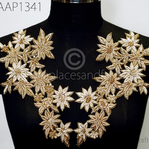 Puede incluir: Aplique floral dorado con un diseño delicado. El aplique está hecho de lentejuelas y cuentas y es perfecto para agregar un toque de elegancia a cualquier prenda.