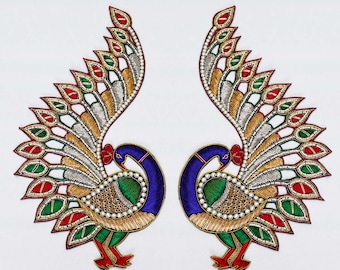 May include: A pair of symmetrical peacock-shaped embroidered patches labeled AAP-978. Each patch features a blue neck, green and gold body, and a fanned tail with red, green, and silver accents, all outlined with white beads and metallic thread.