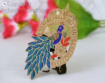 May include: Gold embroidered peacock design with blue, green, and red thread. The peacock is surrounded by a gold frame with intricate details.