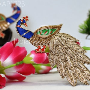 Pode incluir: Um remendo de bordado de pavão dourado e azul com um design verde e dourado. O pavão tem uma cauda longa de penas douradas. O remendo é perfeito para adicionar um toque de elegância a qualquer projeto.