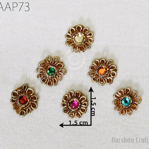 Può includere: Sei decorazioni dorate a forma di fiore con strass colorati al centro. Ogni decorazione misura 1,5 cm di diametro.