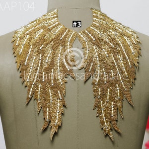 May include: Gold beaded applique with a feather design. The applique is shaped like a collar and has a #3 tag attached.