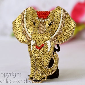May include: Gold sequined elephant hair tie with red and white accents.