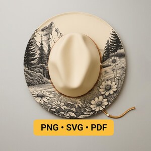 May include: A cream-coloured fedora hat with a wide brim, featuring a black and white mountain and floral landscape design. The hat has a brown leather band and a chin strap. The text "PNG • SVG • PDF" is displayed on a yellow rectangle.
