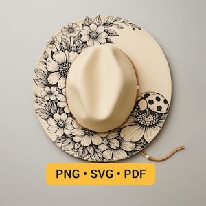 May include: A cream-colored hat with a wide brim, adorned with black floral and leaf designs. A ladybug is painted on the brim. The hat has a tan leather band and a chin strap. The text "PNG • SVG • PDF" is displayed on a yellow rectangle.