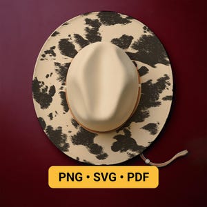 May include: A cream-colored cowboy hat with a cowhide print brim and a matching crown. The hat features a brown leather band and a chin strap. The image also includes the text "PNG • SVG • PDF" in a yellow rectangle.