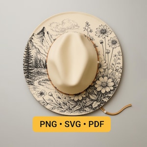 May include: A cream-coloured hat with a beige crown and a wide brim. The brim features a black and white mountain and floral design. The hat has a brown leather band and a chin strap. The text "PNG • SVG • PDF" is on a yellow rectangle.