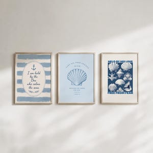May include: Three framed art prints with nautical themes. One features blue stripes and an anchor with text. Another has a seashell graphic and text. The third print displays various seashells and text.