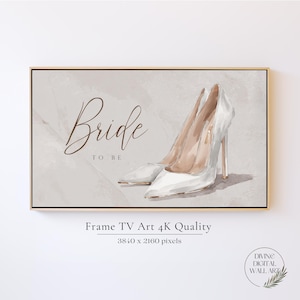 Peut inclure: Une impression d'art numérique pour téléviseur encadré représentant une paire d'escarpins blancs à talons hauts sur un fond beige clair. Le texte "Bride TO BE" est écrit en brun. La résolution de l'image est de 3840 x 2160 pixels.