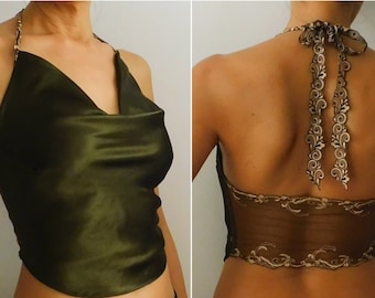 May include: A halter top with a cowl neck and a satin-like fabric. The top is a dark green colour and has a brown lace trim around the neckline and straps. The straps are tied at the back of the neck with a bow.