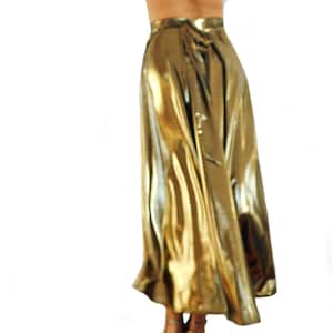 May include: A full-length, gold metallic skirt with a high waist and a flowing silhouette. The skirt is made of a shiny, reflective material and has a tie at the waist. The skirt is suitable for special occasions.
