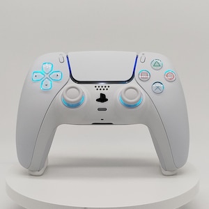 May include: A white wireless video game controller featuring a central touchpad, two analogue sticks, a directional pad, and four action buttons. The controller includes integrated light strips that emit a soft blue glow around the buttons and sticks.