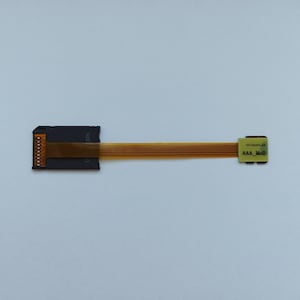 May include: A black adapter with a gold ribbon cable. The adapter has the text "SD12E" printed on it. The cable has the text "AAA_M00" printed on it.