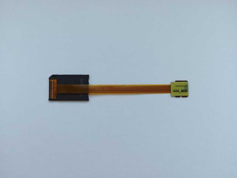 May include: A black adapter with a gold ribbon cable. The adapter has the text "SD12E" printed on it. The cable has the text "AAA_M00" printed on it.