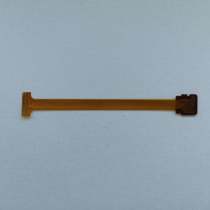 May include: A gold-coloured flexible circuit board with a connector on each end. The board is about 25 cm long.