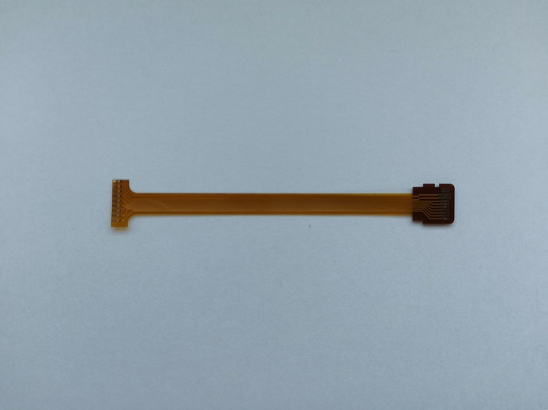 May include: A gold-coloured flexible circuit board with a connector on each end. The board is about 25 cm long.