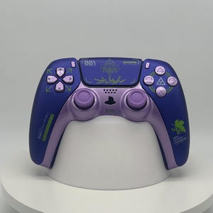 Può includere: Un controller PlayStation 5 personalizzato in una combinazione di colori viola e blu. Il controller presenta un design unico con testo e simboli giapponesi. I pulsanti e i joystick sono viola e il controller ha una finitura opaca.