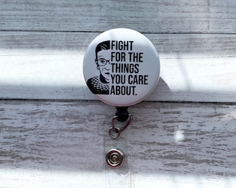 May include: White button with a black and white image of Ruth Bader Ginsburg and the text "FIGHT FOR THE THINGS YOU CARE ABOUT."
