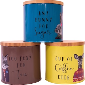 May include: Three metal canisters with bamboo lids. The canisters are teal, brown, and yellow. The teal canister has a rabbit illustration and the text "Any bunny for sugar". The brown canister has a fox illustration and the text "Too foxy for tea". The yellow canister has a deer illustration and the text "Cup of coffee deer".