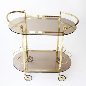 Vintage unieke neoklassieke ovale messing barwagen, sierlijke trolley uit de jaren 60 met gerookt glas, Hollywood Regency-cocktailwagen, theewagen
