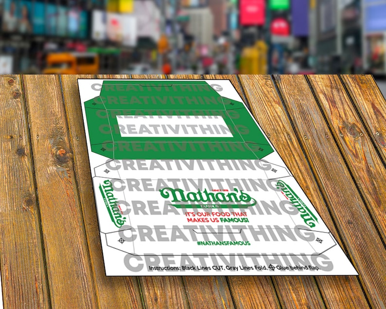 K&ouml;nnte beinhalten: Eine druckbare Vorlage f&uuml;r eine Nathan's Famous Hotdog-Box. Die Vorlage ist wei&szlig; mit schwarzen Schnittlinien und grauen Faltlinien. Die Vorlage zeigt das Nathan's Famous Logo und den Text "It's our food that makes us famous!" mit dem Hashtag #NATHANSFAMOUS.