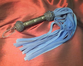 Flogger en cuir daim bleu avec détail de poignée noir et bleu.