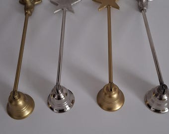 May include: Four decorative metal table place card holders. Two are gold with a deer head design, one is gold with a star, and one is silver with a star. Each has a bell-shaped base.