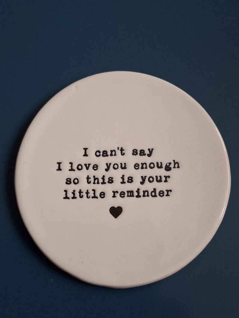 May include: White ceramic dish with black text that reads "I can't say I love you enough so this is your little reminder" with a small black heart.