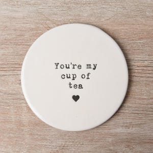 May include: White ceramic coaster with the text "You're my cup of tea" in black typewriter font and a small black heart.