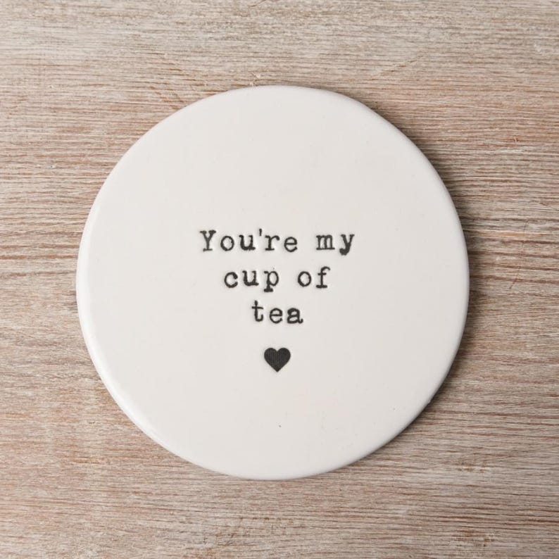May include: White ceramic coaster with the text "You're my cup of tea" in black typewriter font and a small black heart.