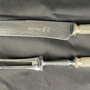 May include: A silver knife and fork set with a textured handle. The knife has a long, sharp blade and the fork has two prongs.