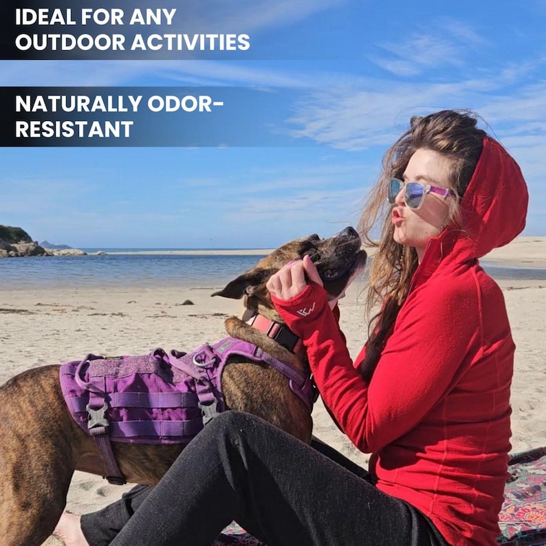 May include: A woman wearing a red hooded jacket and sunglasses is on a beach with a dog. The dog wears a purple harness. Text on the image reads: "IDEAL FOR ANY OUTDOOR ACTIVITIES" and "NATURALLY ODOR-RESISTANT".