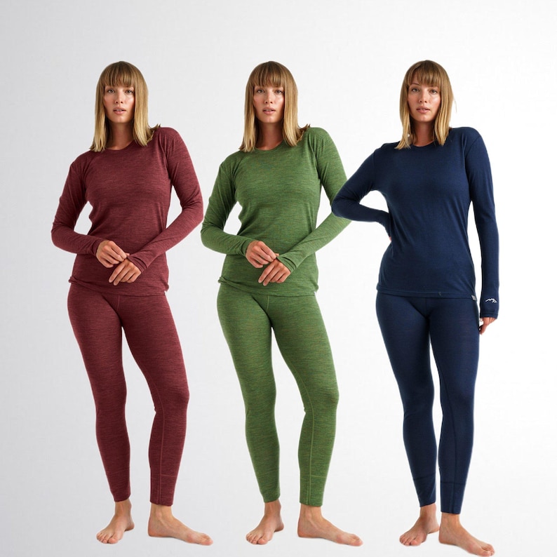 May include: Three sets of long-sleeved base layer shirts and matching leggings in solid colors: deep burgundy, olive green, and navy blue. Each set features a crew neckline, long sleeves, and fitted pants with visible seams at the ankles.