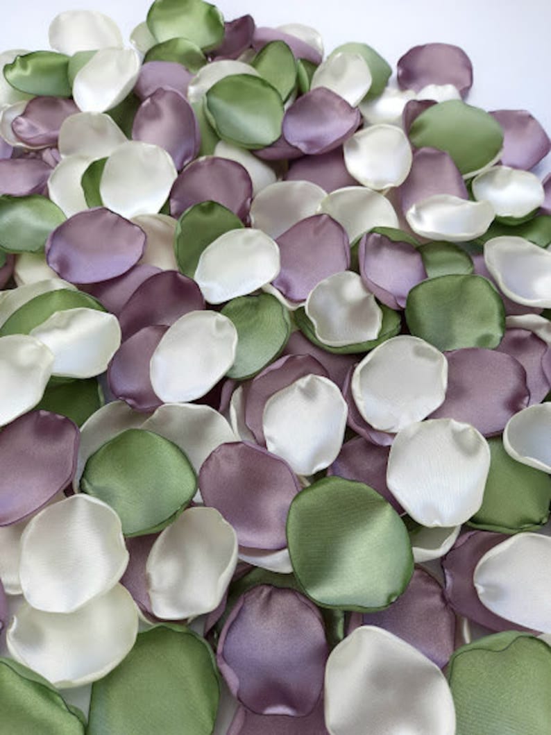 Pu&ograve; includere: Una collezione di petali di fiori di seta in tonalit&agrave; avorio, rosa polvere e verde salvia. I petali sono sparsi su una superficie bianca.